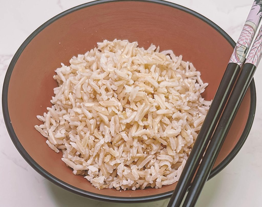 bowl of cooked brown rice with chopsticks