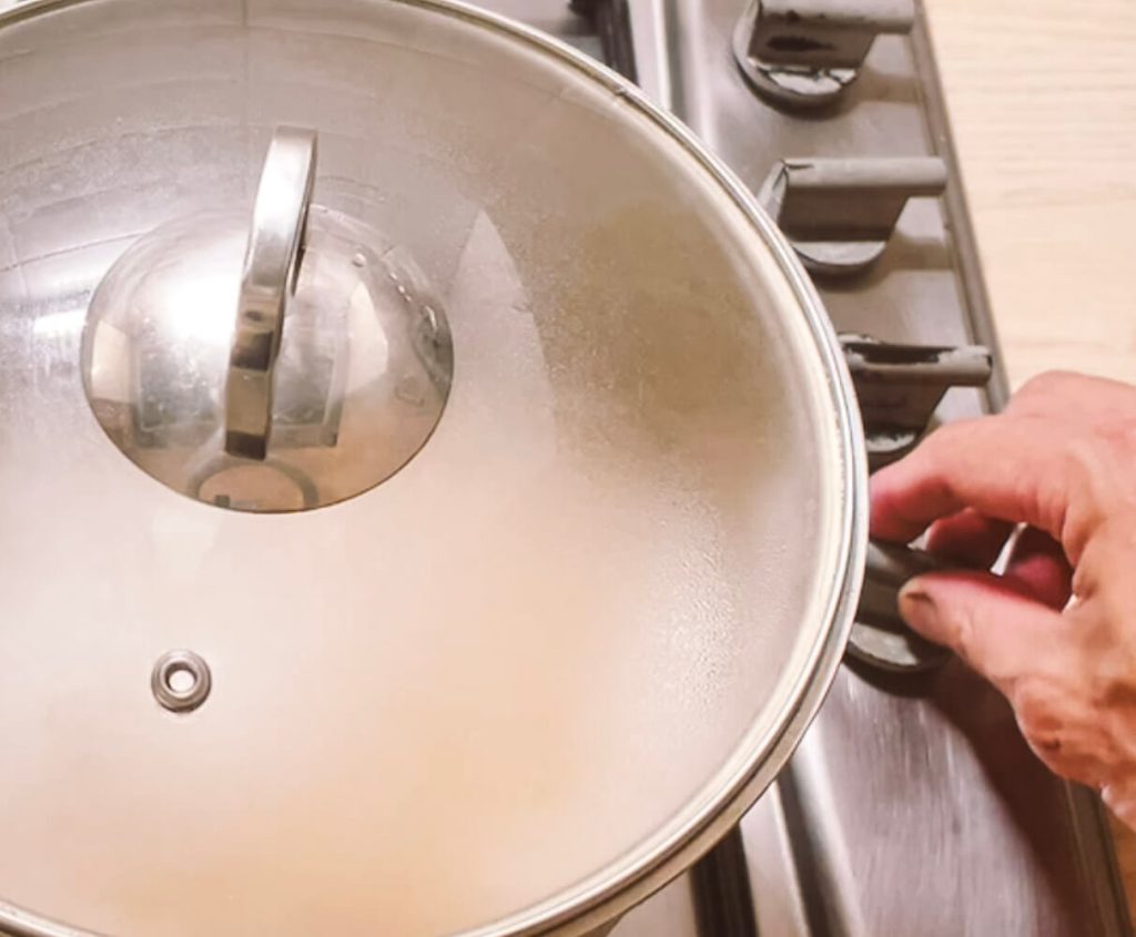 Covering pot and reducing heat to simmer for brown rice cooking