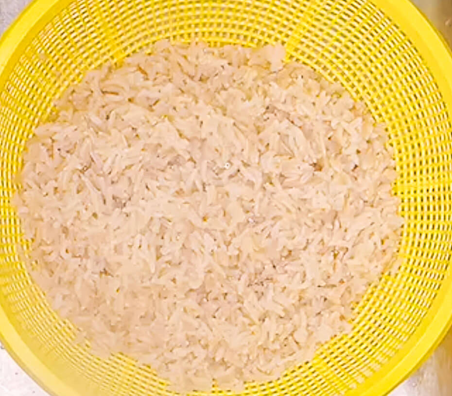 Brown rice drained in strainer after boiling ready for steaming