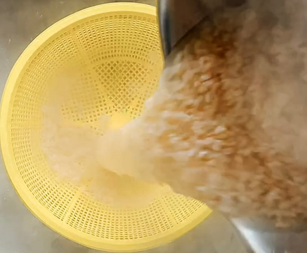 Draining cooked brown rice in a colander after boiling