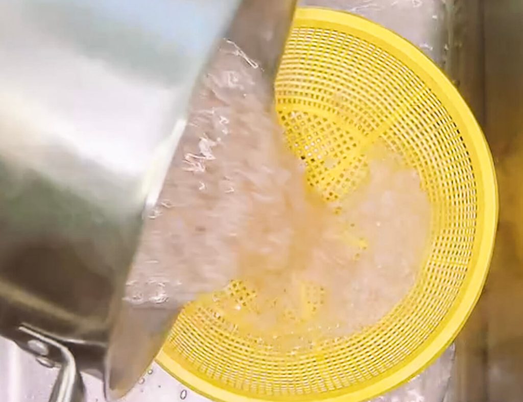 Draining brown rice in strainer after boiling method