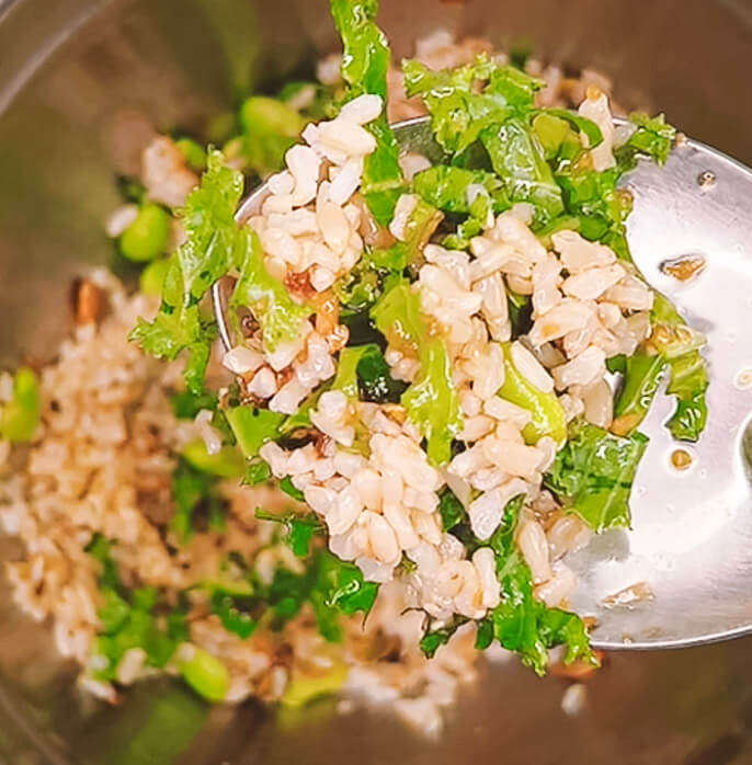 tossing brown rice salad with kale pumpkin beetroot and Japanese onion dressing