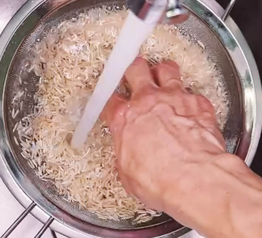 gently washing brown rice by hand in bowl under water