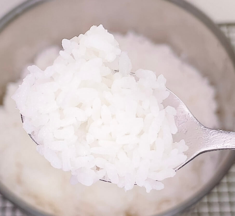 Fluffy cooked white rice on a spoon using the absorption method