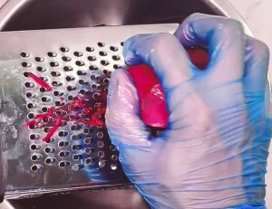 grating raw beetroot on a box grater for brown rice salad