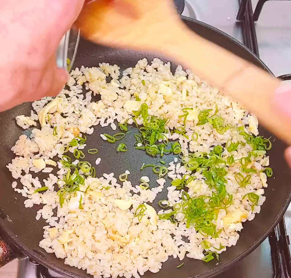 Adding green onion to fried rice before final seasoning