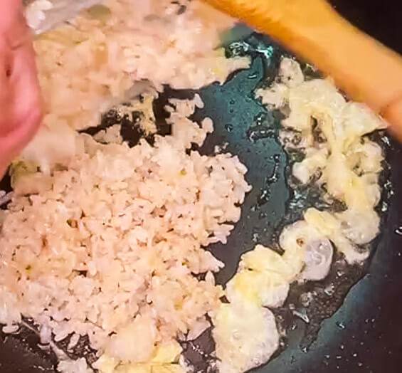 Adding rice to egg in pan for chicken fried rice