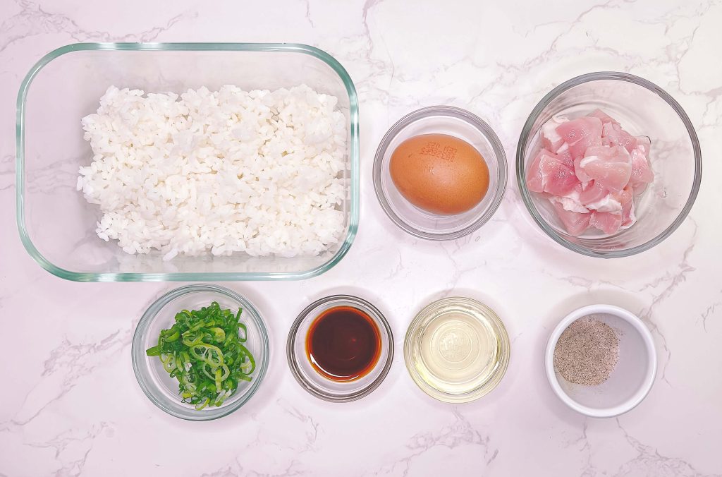 Chicken fried rice ingredients including rice, chicken, egg, soy sauce and spring onion