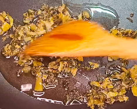 Sauteing takana pickled mustard greens in a pan before adding rice