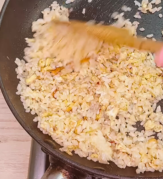 Adding rice to garlic butter and egg in pan for garlic fried rice