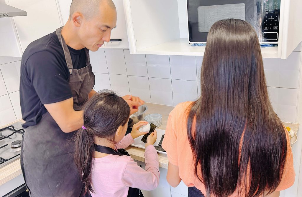 Kenji teaching his daughters how to cook