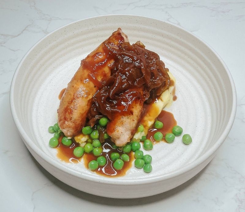 Bangers and mash with teriyaki onion gravy and peas